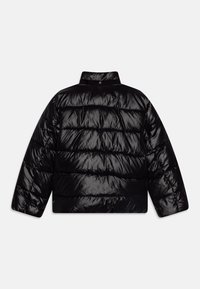 Fekete, fényes, steppelt puffer dzseki magas gallérral és hosszú ujjakkal, hátulról látható, világos egyszínű háttér előtt.