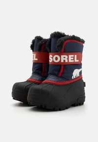 Blaue Winterstiefel mit roten und weißen Riemen, einem Warmfutter an der Oberseite und Gummisohlen, die über ein strukturiertes Griffmuster verfügen.