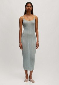 Lichtblauwe geribde midi-jurk met dunne bandjes, een getailleerd silhouet en een lichtrafelzoom, gecombineerd met transparante instap ballerina's.