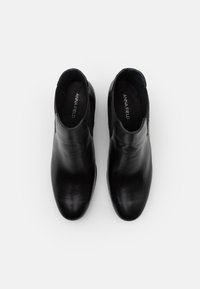 Bottes cheville en cuir noir à texture lisse, bout arrondi et panneaux latéraux élastiques. Logo de la marque visible sur la semelle intérieure.