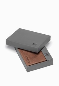 Brown leather wallet with a soft texture, presented in a gray box. The wallet features embossed branding and contrasting stitching.