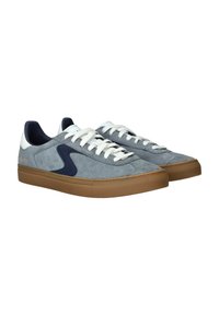 Zapatillas de ante en gris claro con detalles en azul marino y cordones blancos. Cuentan con una suela de goma y una lengüeta en el talón de color contrastante. Diseño minimalista.