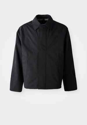 Veste noire courte avec col évasé, deux poches avant et manches longues. Fabriquée dans un matériau lisse et léger avec un branding subtil.