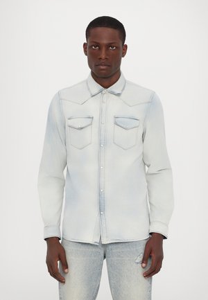 Light blue denim shirt with long sleeves, pointed collar, two chest pockets, and button closure. Features fading and subtle stitch detailing.