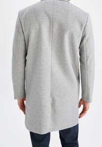 Grå uldblandet frakke med lige snit, lange ærmer og minimal dekoration. Har en enkelt søm ned ad ryggen og et mellemlangt design.