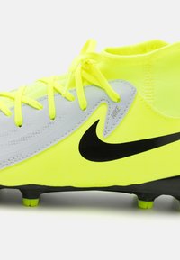 Futbalová kopačka Nike v jasne žltej farbe s šedými akcentmi. Má štruktúrovaný zvršok, čierny logo swoosh a kontrastné kopačky na podrážke.