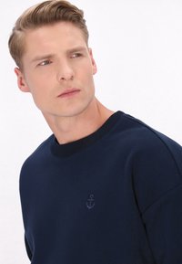 Marineblaue Sweatshirt aus Baumwollmischung, mit einem gerippten Ausschnitt und einem dezenten Ankerlogo auf der Brust gestickt.
