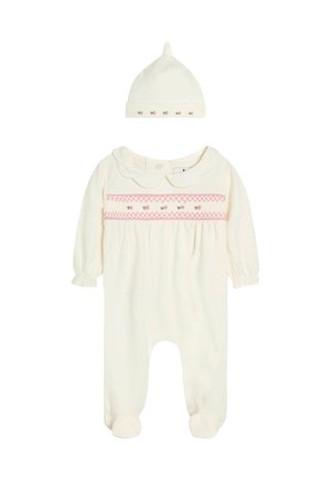 Babykleidung in Cremetönen mit rosa besticktem Blumenband und passender Mütze mit kleiner Blumenstickerei auf weißem Hintergrund.