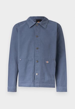 Blå skjortejakke med krave, to forlommer, metaltrykknapper og lille logopatch på højre lomme.