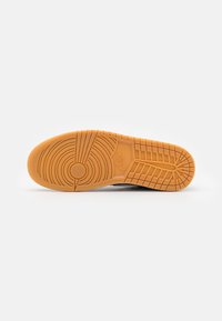 Semelle d'une basket avec des motifs circulaires et à quadrillage, de couleur marron clair, avec un logo Nike au centre.