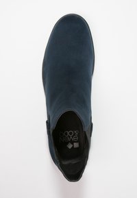 Bottes chelsea en daim bleu marine avec panneaux latéraux élastiques et une texture lisse. Bout rond et semelle plate. Logo visible à l'intérieur.