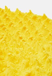 Textured yellow fabric featuring raised, cone-like protrusions with fine detailing, creating a tactile, three-dimensional pattern.