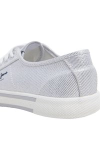 Sömlös silver sneaks med strukturerad ribbad ovandel, vit sula och logotyp på sidan; designad för vardagsbruk med en låg silhuett.