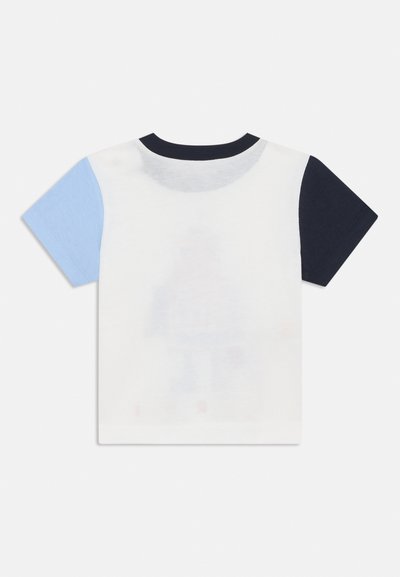 Camiseta de manga corta en blanco con mangas en contraste azul claro y marino. Tejido suave, cuello redondo y un diseño impreso sutil en la parte posterior.