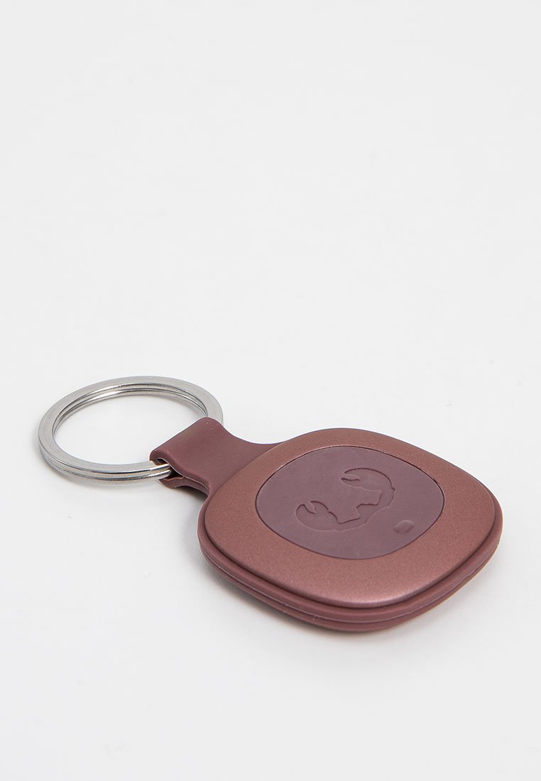 Breloczek w stonowanym burgundowym odcieniu, o gładkim, zaokrąglonym kształcie z centralnym wytłoczonym logo i srebrnym uchwytem na klucze.