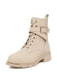 Beżowe kozaki za kostkę wykonane z teksturowanej skóry, z wiązanym zapięciem, złotymi detalami oraz masywnym obcasem z paskiem i klamrą.