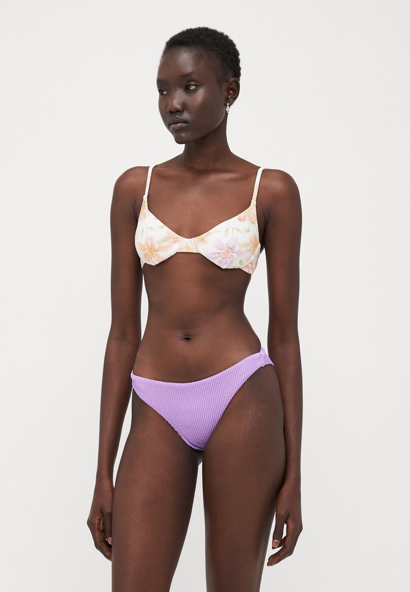 Top bikini floreale con parte inferiore in lavanda texture. Il top presenta coppe morbide e spalline sottili, mentre la parte inferiore ha un motivo a coste.