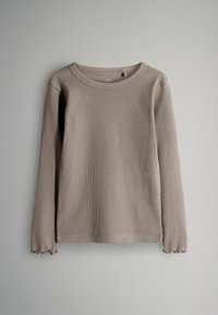 Taupe ribbad långärmad tröja med rund halsringning och subtila volangdetaljer vid ärmarna, visad mot en enfärgad bakgrund.