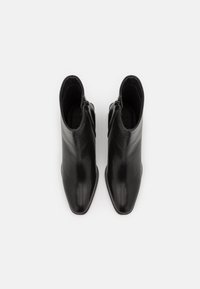 Černé kožené kotníkové boty s elegantním designem, špičatou špičkou a zadním zipem. Hladká textura a štíhlý silueta.