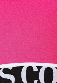 Rosa textil med en mjuk textur har ett svartvitt logoband i botten som kontrasterar mot den livfulla bakgrunden.