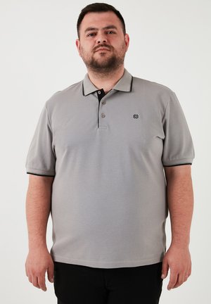 Šedé polo tričko s texturovaným povrchem, černými akcenty na límci a rukávech, tříknoflíkovým zapínáním a malým logem na levém hrudníku.