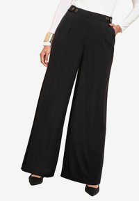 Černé kalhoty s širokými nohavicemi vyrobené z hladké, splývavé tkaniny. Mezi vlastnosti patří vysoký pas, přední skladby a akcenty zlatých knoflíků.