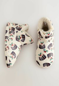 Fleece-foranede hjemmesko med en cremefarvet bund prydet med et mønster af julesovs og hyldeblade; blød struktur, rund form, hyggeligt design.