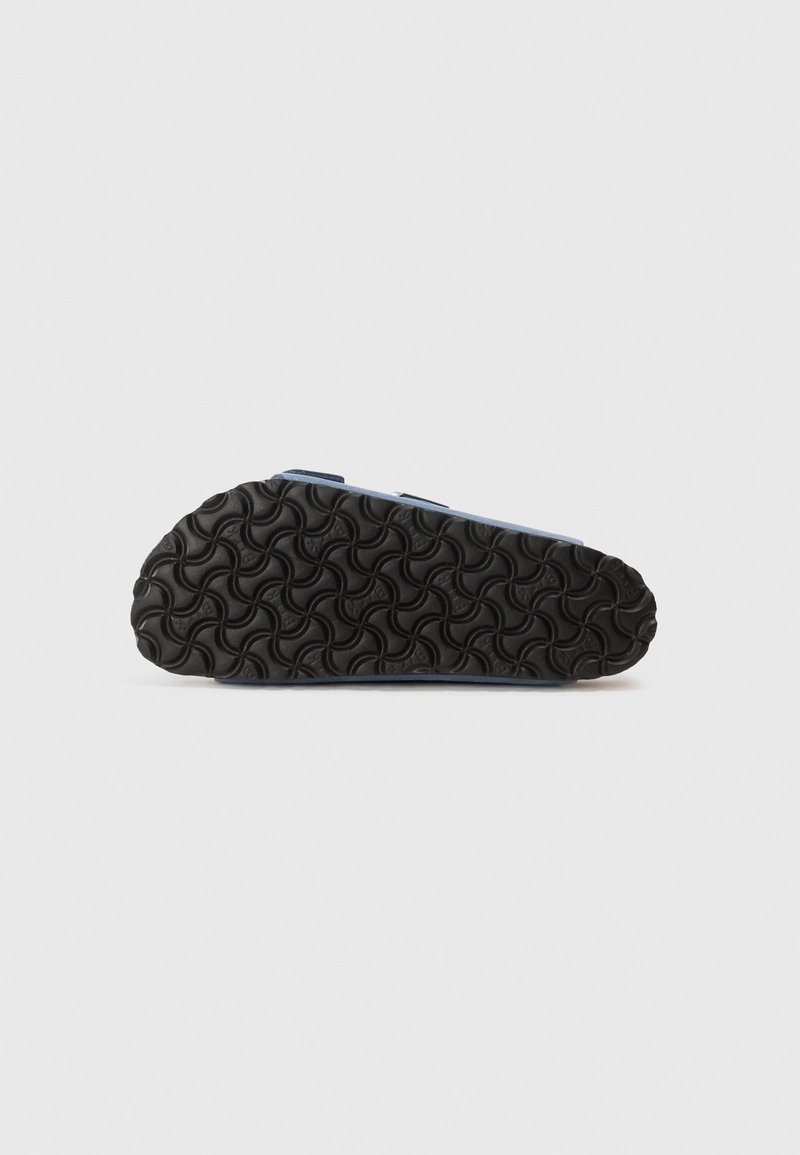 Blauer Schuh mit einer strukturierten schwarzen Gummisohle, die ein wellenförmiges Muster aufweist. Das Material scheint synthetisch zu sein und hat verstellbare Riemen im oberen Bereich.