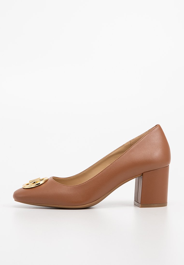 Bruine leren damesschoenen met blokhak en een gouden decoratief embleem op de teen, in profiel weergegeven op een witte achtergrond.