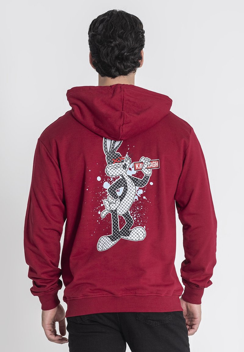 Felpa rossa con cappuccio, caratterizzata da una grande grafica stampata di un personaggio dei cartoni animati sulla schiena, con dettagli in bianco e nero e schizzi blu.