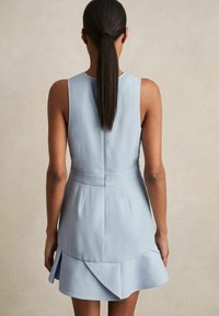 Abito senza maniche azzurro chiaro con orlo plissettato e arricciato, corsetto aderente e una texture di tessuto liscia. La vista dal retro mostra un design a linea pulita.