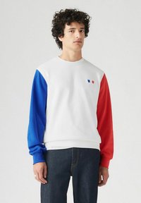 Witte sweatshirt met blauwe en rode mouwen, voorzien van een klein embleem. Gemaakt van zachte stof, met ribgebreide manchetten en onderrand.