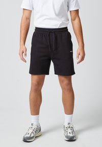Zwarte katoenen shorts met een elastische tailleband en trekkoord. De shorts hebben een zijlogo-detail en een ontspannen pasvorm.