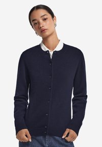 Marineblauer Cardigan aus weichem Stoff, mit rundem Ausschnitt, langen Ärmeln, Knopfverschluss sowie geripptem Saum und Bündchen.