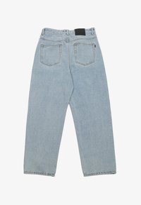 Light blue denim jeans with a relaxed fit, featuring two back pockets and a black leather patch at the waistband. Stitching is visible.