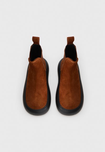 Pruuni nubuk nahast pahkluu saapad musta kummist tallaga, sileda tekstuuriga ja taga tõmbejõu abil. Ümar varvas ja stiilne disain.