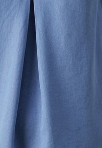 Vaaleansininen puuvillakangas, jossa on pehmeä pinta ja hienovarainen kiilto, esittelee laskeutuvan muotoilun ja hienostuneen, sileän viimeistelyn.