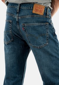 Jeans de denim en azul oscuro, con un clásico diseño de cinco bolsillos, costuras en contraste y un parche de cuero con la marca en la parte trasera.