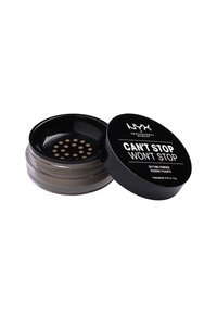 Genomskinligt settingpuder i en svart cirkulär behållare, med en klar botten, en bred öppning med små hål och fet vit text.