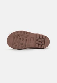 Suola di scarpa in gomma di colore marrone scuro con motivi di presa testurizzati. Presenta un design piatto con punta arrotondata e battistrada dettagliato per una maggiore aderenza.