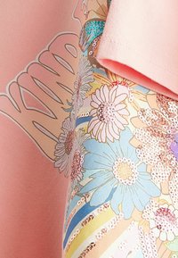 Tela de sudadera rosa con diseño floral colorido y lentejuelas. Presenta una textura suave, un corte relajado y mangas cortas.