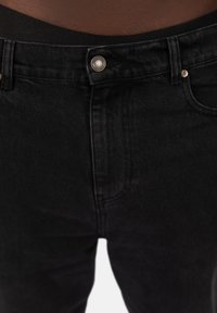 Svarta denimjeans med en slät textur, klassisk femficksdesign, glänsande metallknapp och en något elastisk midja för komfort.