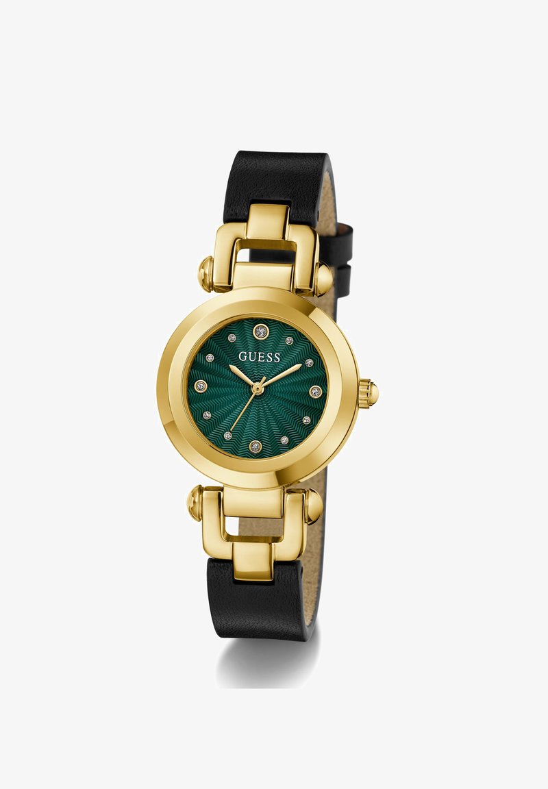 Montre ronde dorée avec cadran vert texturé, index en cristal, bracelet en cuir noir et logo Guess à la position 12 heures.