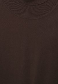 Gros plan sur le tissu d'un pull à col rond côtelé de couleur brun foncé, montrant la texture du tricot.