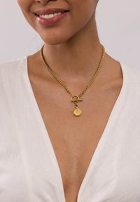 Goldkette mit einem gedrehten Design, ausgestattet mit einem Toggle-Verschluss und einem runden Anhänger mit einem kleinen Diamantakzent.
