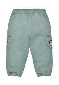 Pantaloni della tuta verde menta con vita e polsini elastici. Presentano due tasche laterali con toppe di animali su ciascun ginocchio. Texture morbida.