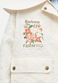 Λευκό μπουφάν με λούκια και λουλουδάτο σχέδιο που περιλαμβάνει πορτοκαλί και λευκά λουλούδια και κείμενο "Barbour FARM RIO" στο καπάκι της τσέπης στο στήθος με ορειχάλκινα κουμπιά.