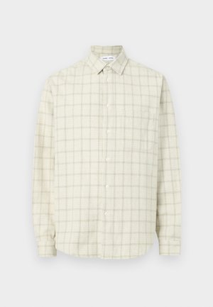 Beež värvusega nööbitav särk pikkade varrukatega ja peene ruudulise mustriga, millel on terav krae ja üks rindtasku, ühevärvilisel taustal.