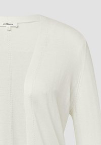 Leichter, cremfarbener Cardigan aus weichem Stoff. Mit V-Ausschnitt, subtiler Textur und sauberen Kanten. Das Etikett zeigt Marke und Größe.