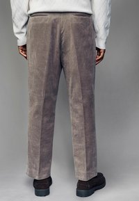 Corduroy pants in gray with vertical ribbing, featuring a straight-leg design and side pockets, paired with dark footwear.